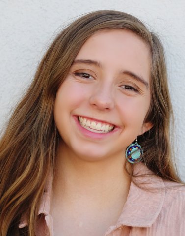 Niwot High school graduate in a pink shirt and earrings. 