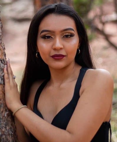 Olde Columbine High Graduate in a black shirt leaning on a tree. 