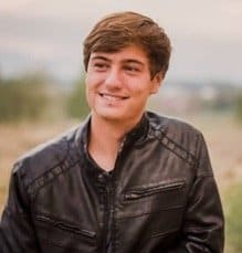 Graduate in a black leather jacket posing outdoors. 