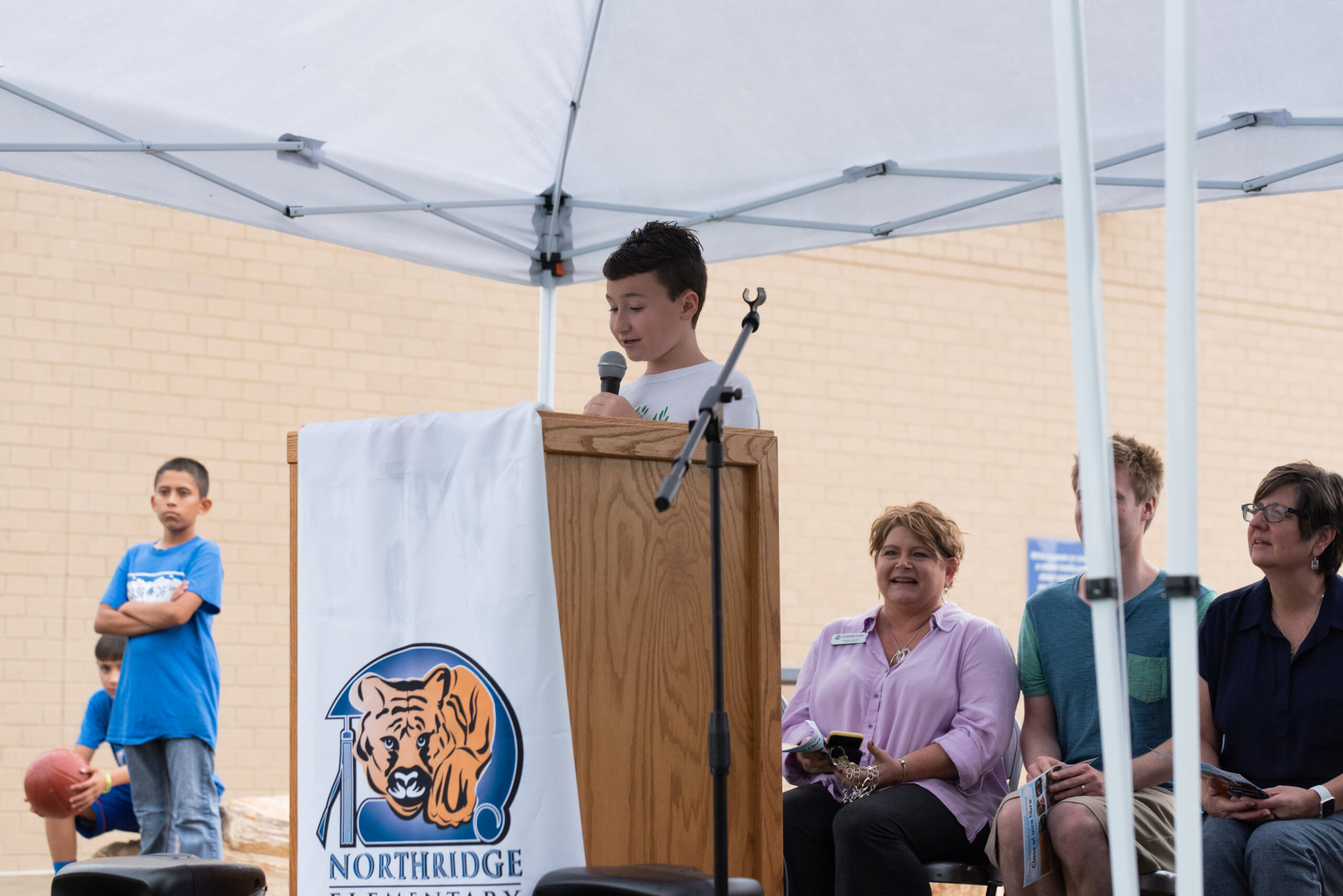 An elementary aged student speaking at a podium to open the new outdoor learning space. 