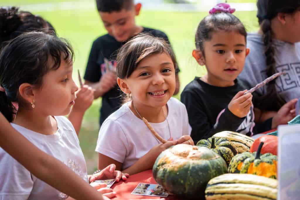 Los alumnos sonríen mientras observan diferentes verduras.