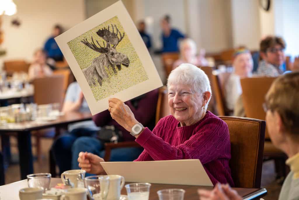 Atria resident receiving art work from Skyline student