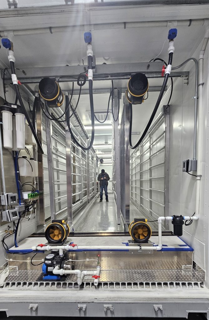 Interior of a facility with metal shelving, pipes, and a person standing in the center, surrounded by equipment.