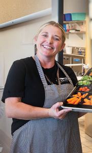 Staff member at St. Vrain Valley Schools serving food with a smile.
