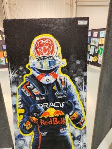 A colorful painting of a race car driver in a helmet and racing suit, featuring logos and a celebratory pose.