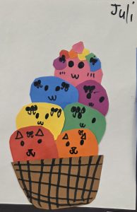 Colorful paper ice cream cones with cute faces stacked in a brown basket, created by Juli.