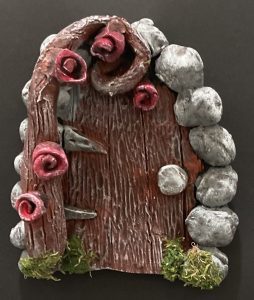 A decorative door with a wooden texture, surrounded by gray stones and pink roses, set against a black background.