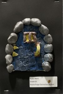 A textured blue door framed by gray stones, with yellow accents, displayed as an art piece by a third grader.