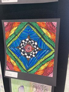 Colorful geometric drawing featuring a central circular pattern with vibrant blue, green, red, and yellow sections.