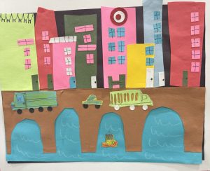 Colorful paper collage depicting a cityscape with buildings, vehicles on a bridge, and water below.