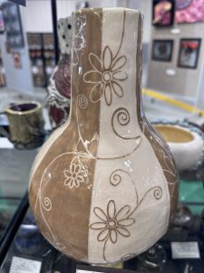 A decorative vase with a split design in brown and cream, featuring floral and swirl patterns.