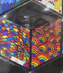 Colorful artwork featuring zigzag patterns and rainbow waves, created by fourth graders Seth and Isabel.