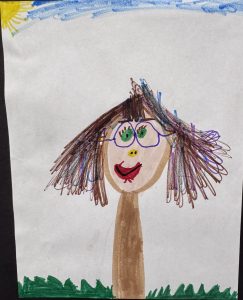 A child's drawing of a person with brown hair, glasses, and a smiling face, set against a sunny sky and grass.
