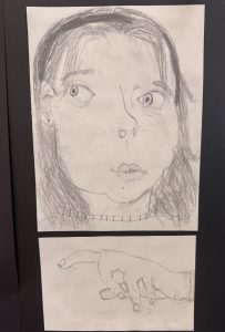 A pencil drawing featuring a surprised face above a hand pointing, both on separate sheets of paper.