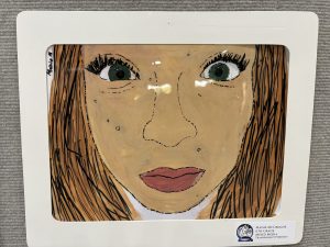 A mixed media portrait of a girl with green eyes and brown hair, featuring a neutral expression and subtle details.