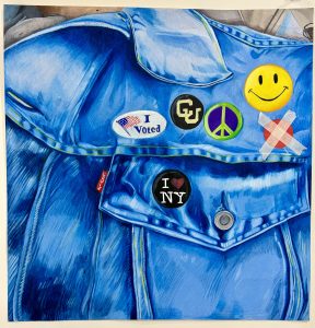 A close-up of a blue denim jacket featuring various colorful buttons, including "I Voted" and "I ❤️ NY."