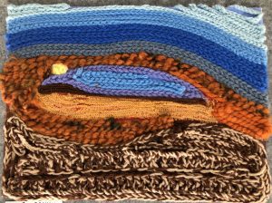 Textile artwork featuring layered yarns in blue, orange, and brown, creating a textured landscape scene.