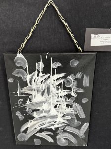 A black canvas painting featuring abstract white shapes resembling mountains and swirling clouds.