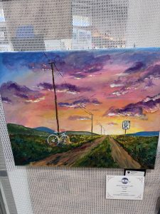 A colorful sunset landscape with a dirt road, power lines, and a white bicycle leaning against a post.