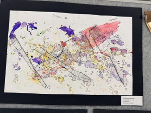Obra de arte abstracta y colorida en la que aparecen pinceles y salpicaduras de acuarela en diversos tonos, firmada con el nombre del artista.