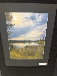 Un paisaje sereno en el que se ve un río rodeado de una exuberante vegetación bajo un cielo nublado, enmarcado en negro.