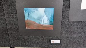 Una acuarela que representa una cascada rodeada de árboles, montada sobre un fondo oscuro y provista de una etiqueta del artista.