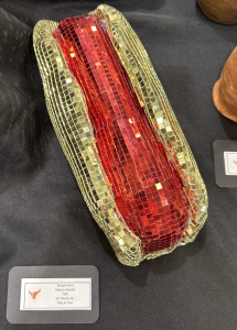 Art piece titled "Boogie Buns" by Margo Feaster, featuring a red mosaic design with gold accents on a black background.