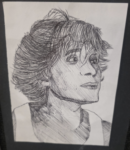 A detailed pen sketch of a young person with tousled hair, looking slightly to the side with a thoughtful expression.