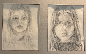 Two pencil sketches of young women, each with long hair and serious expressions, framed and displayed side by side.