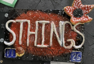 A colorful ceramic sign displaying the word "STHINGS" with a flower decoration, featuring numbers 10 and 26.