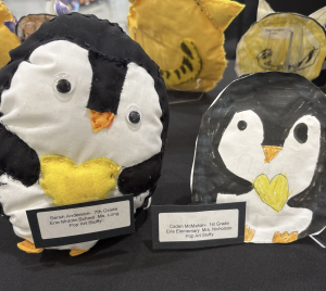 Two penguin-themed art pieces: a plush penguin with a yellow heart and a drawing of a penguin with a heart.