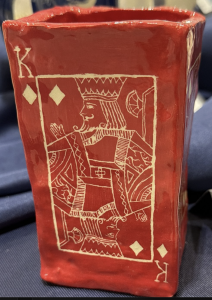 Red ceramic container featuring a king playing card design with diamonds and decorative details.