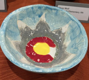 A colorful ceramic bowl with a blue interior and a painted design of a sun with red and yellow accents.