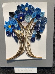 Quilled art piece featuring a blue and black tree with flowers, created by a 7th-grade student.