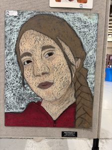 A colorful self-portrait featuring a young person with braided hair, wearing a red hoodie against a textured background.