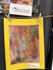 Cuadro abstracto y colorido pintado en acuarela con un borde amarillo, creado por un niño de 4 años en la guardería Spark Discovery.