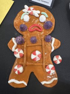 A ceramic gingerbread man decorated with colorful candy details and a surprised facial expression.