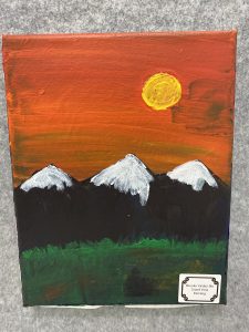 A vibrant sunset over three snow-capped mountains, with a green foreground and a signature label at the bottom.