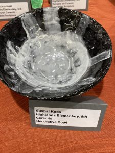 Ceramic bowl featuring a black exterior and white interior, displayed with an identification label.