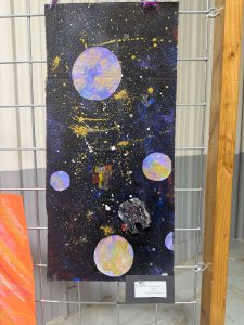 Una colorida ilustración de temática espacial en la que aparecen planetas, estrellas y una nave espacial sobre un fondo negro.