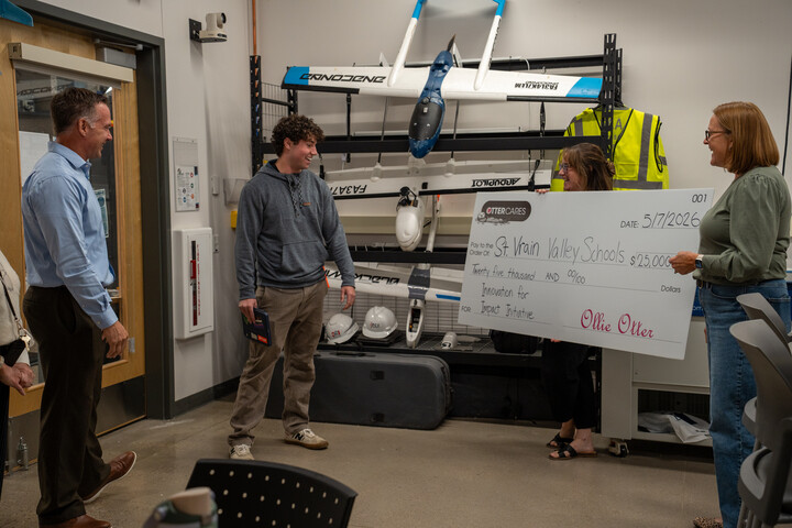 A group of four people in a classroom celebrate a $25,000 check for St. Vrain Valley Schools' innovation initiative.